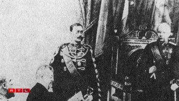 The image shows Duke Adolphe in his capacity as regent present at the Chamber of Deputies's oath-taking session on 11 April 1889. L.J Emmanuel Servais, then-president of the Chamber of Deputies, is reading whilst Adolphe's heir stands at his side.