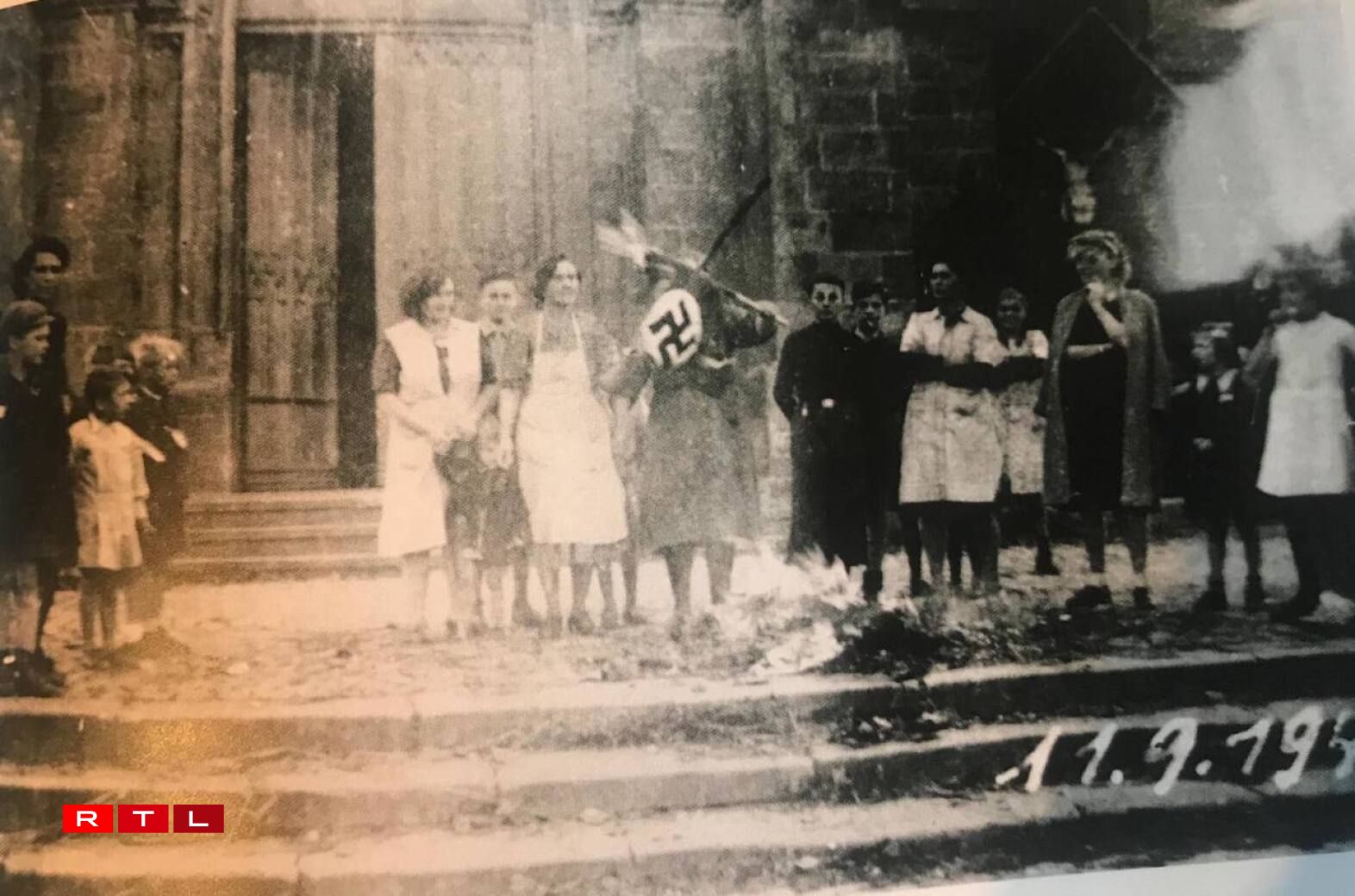 Residents burning Nazi flags in front of the church.