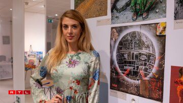 D'Nina Colada, Model a Kënschtlerin, huet eng Fotoausstellung op enger vun de Mauere vum Raum, an entdeckt d'Bedeitung vum Gléck a verschiddenen Deeler vun der Welt.