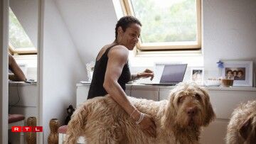 Une femme à côté d'un chien de race Labradoodle.