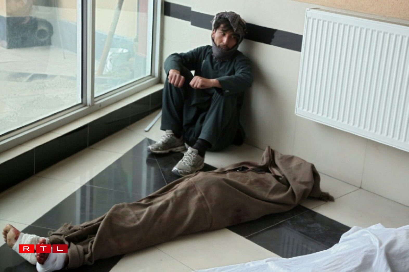 Le parent d'une des victimes de l'attentat contre une école à Kaboul, assis à côté de son corps, le 8 mai 2021