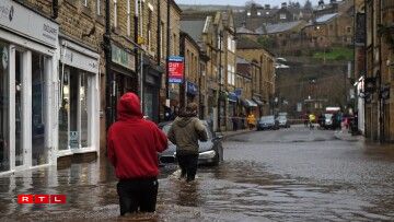 People wade through floodwater in the streets of Hebden Bridge, northern England, on February 9, 2020, as Storm Ciara swept over the country. Britain and Ireland hunkered down Sunday for a powerful storm expected to disrupt air, rail and sea links, cancel sports events, cut electrical power and damage property. With howling winds and driving rain, forecasters said Ciara would also hit France, Belgium, the Netherlands, Switzerland and Germany.