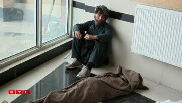 Le parent d'une des victimes de l'attentat contre une école à Kaboul, assis à côté de son corps, le 8 mai 2021