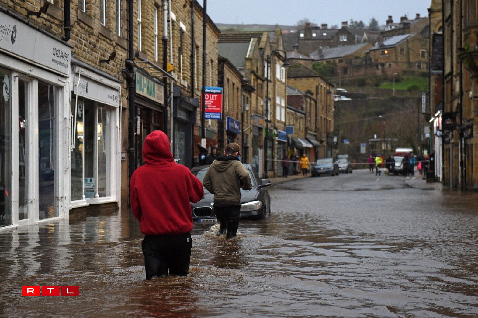 People wade through floodwater in the streets of Hebden Bridge, northern England, on February 9, 2020, as Storm Ciara swept over the country. Britain and Ireland hunkered down Sunday for a powerful storm expected to disrupt air, rail and sea links, cancel sports events, cut electrical power and damage property. With howling winds and driving rain, forecasters said Ciara would also hit France, Belgium, the Netherlands, Switzerland and Germany.