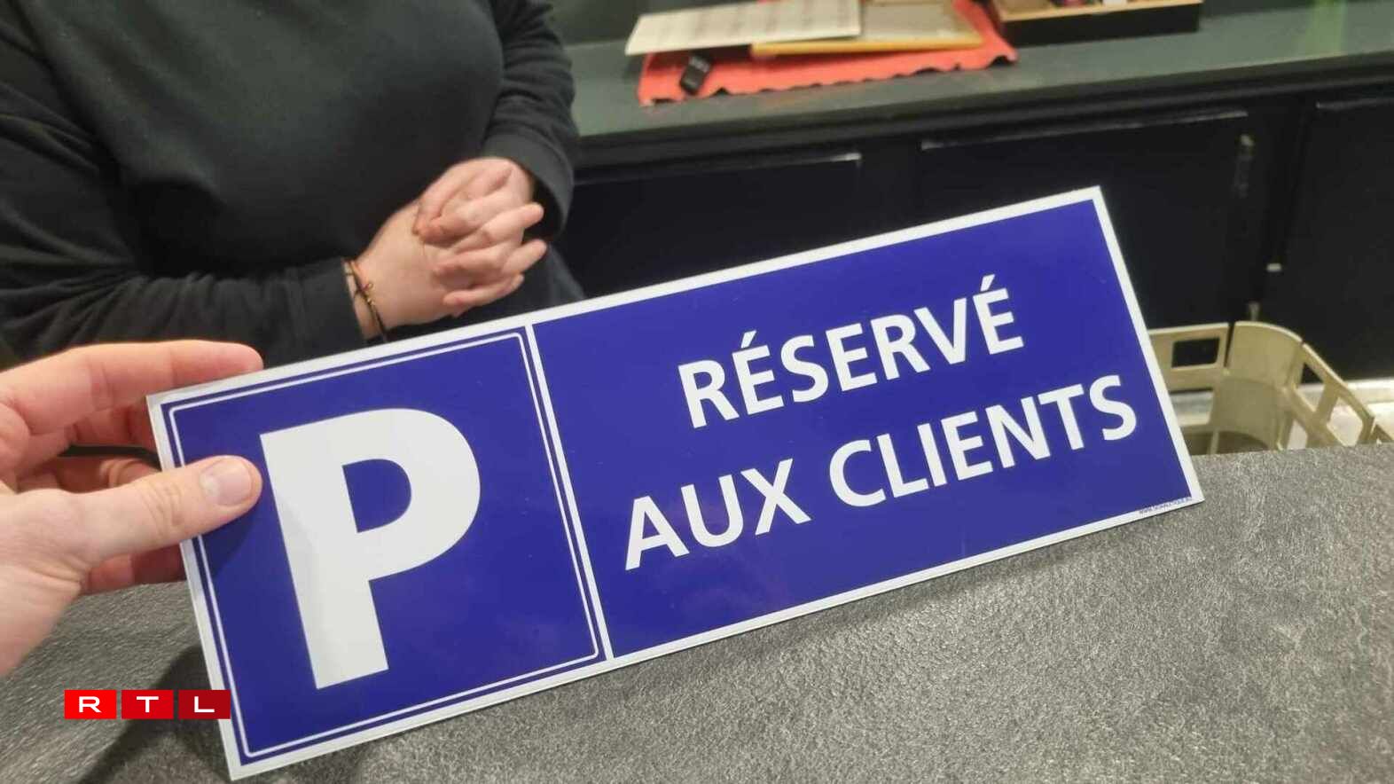 Sheila, serveuse dans un café à Uckange, nous montre le panneau qu'elle aimerait accrocher devant l'établissement pour décourager les frontaliers d'y stationner toute la journée.