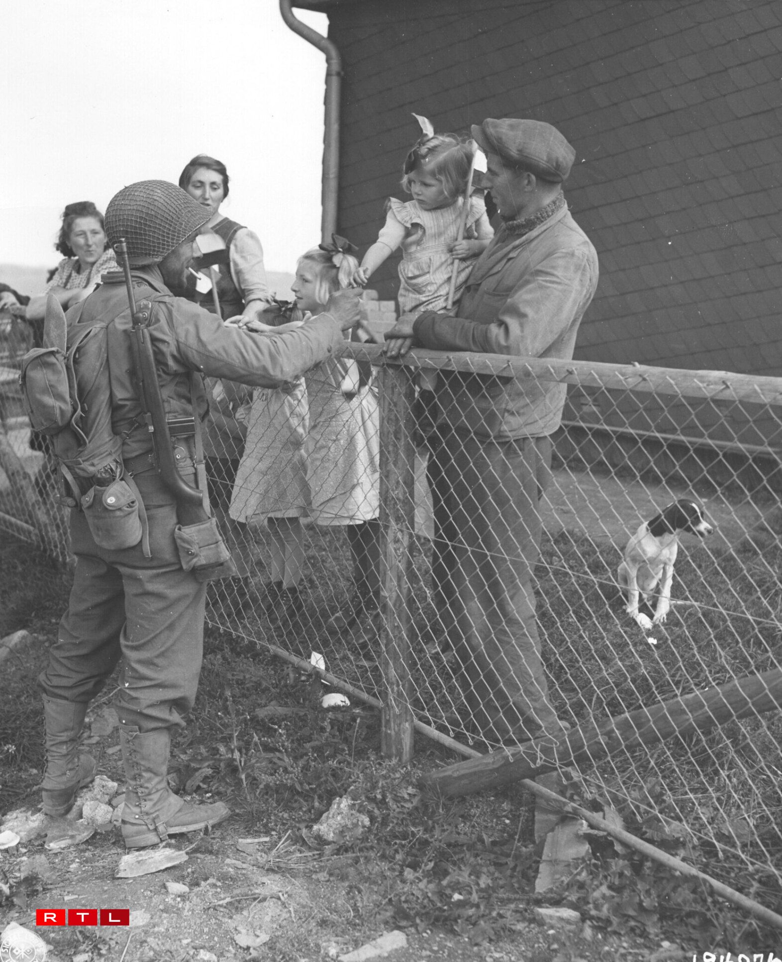 Pvt. Eugene V. Webber, left, of San Leandre, Calif., a member of the 2nd Battalion, 110th Regiment, 28th Division, hands a little girl a stick of chewing gum in the town of Asselbourn, Luxemburg, as he passes through.