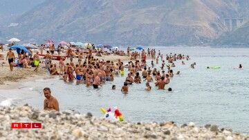 Les Italiens et les touristes se rafraîchissent dans l'eau sur une plage de Messine le 11 août 2021